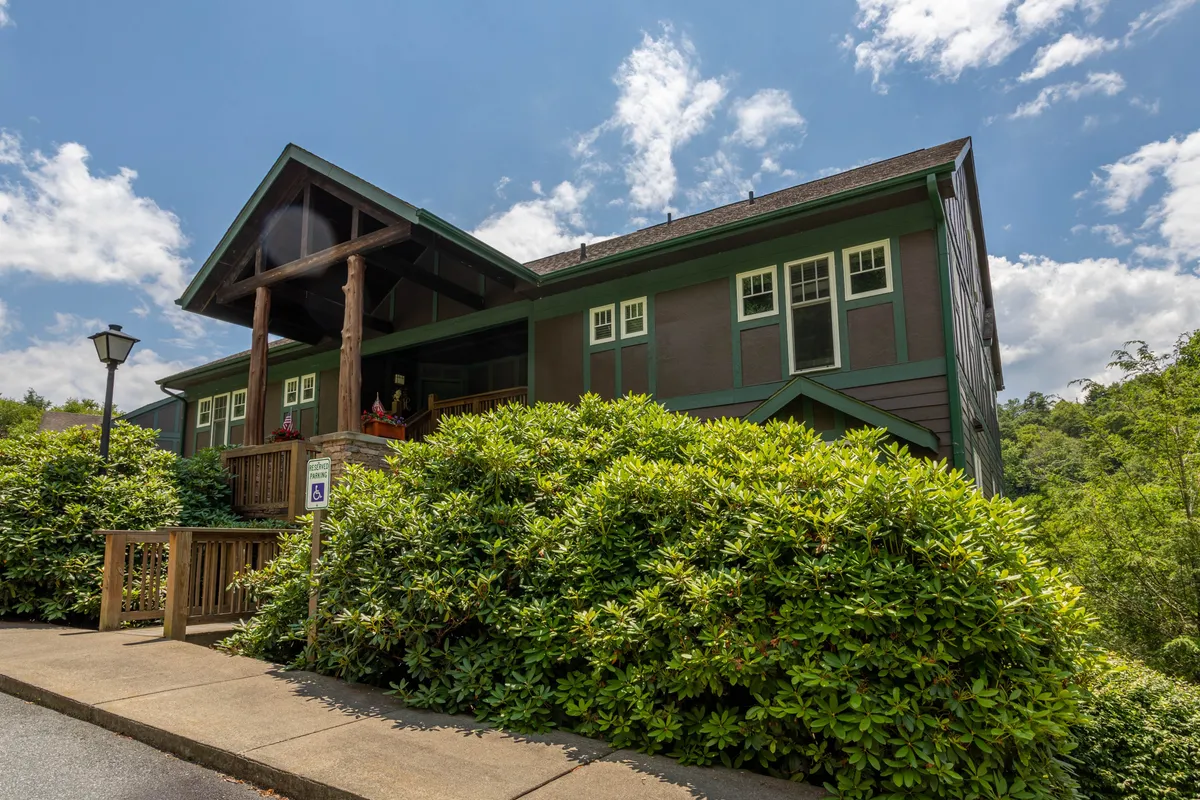 A spacious porch surrounded by lush greenery, displaying the architectural charm of the house and providing a seamless transition from indoor comfort to outdoor enjoyment. The scene suggests relaxation, socializing, and the enjoyment of nature.