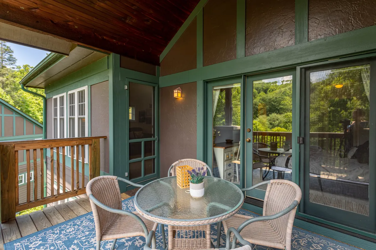 A serene outdoor seating area featuring a glass table, woven chairs with green accents, and a view of the surrounding landscape. The setup is perfect for enjoying a morning coffee or winding down after a day of adventure.